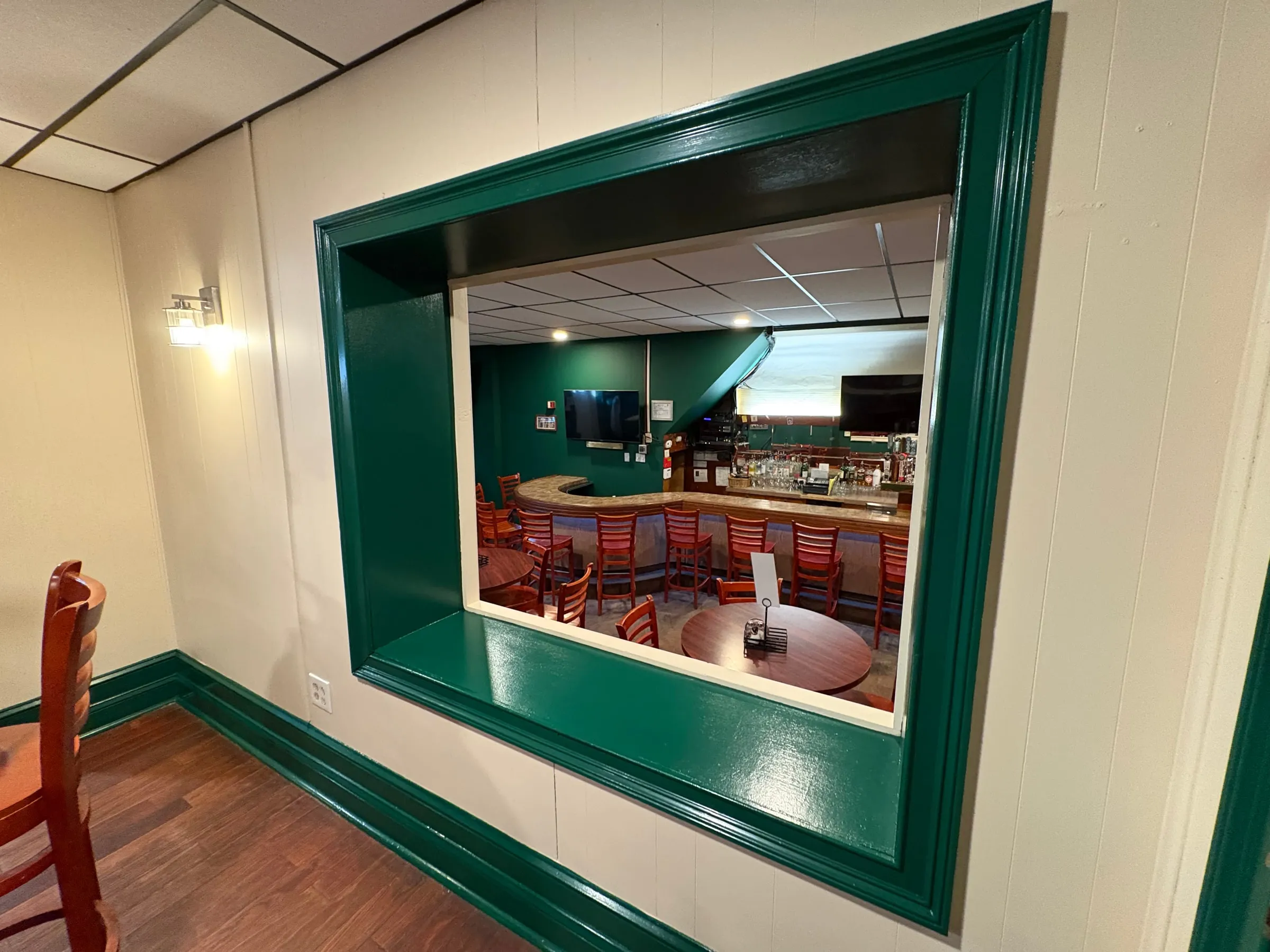 Commercial bar interior with deep green painted trim and pass-through