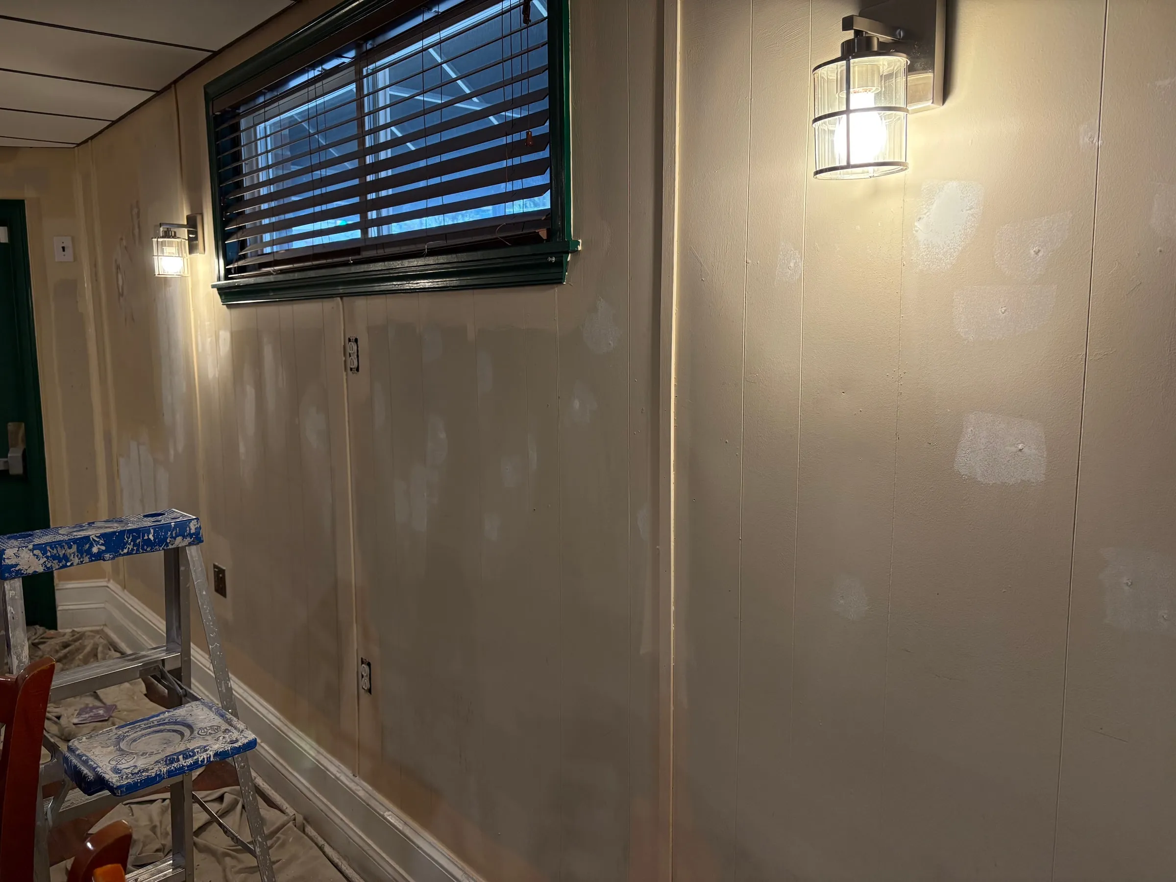 Interior wall being painted with a ladder and drop cloths in place