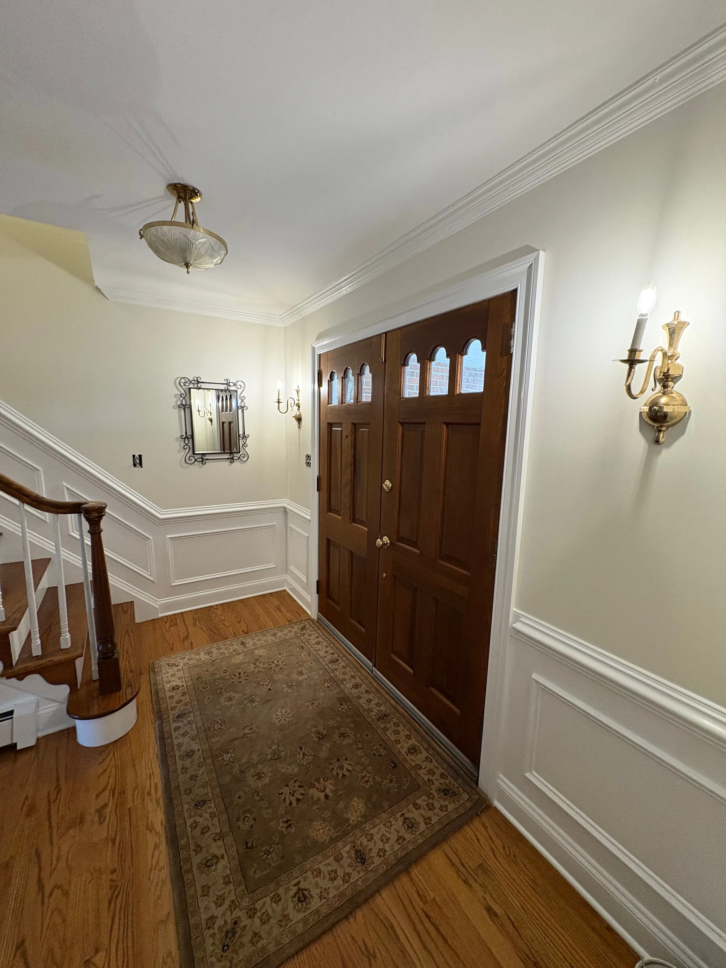 Entry foyer with painted trim, wainscoting and a wood front door